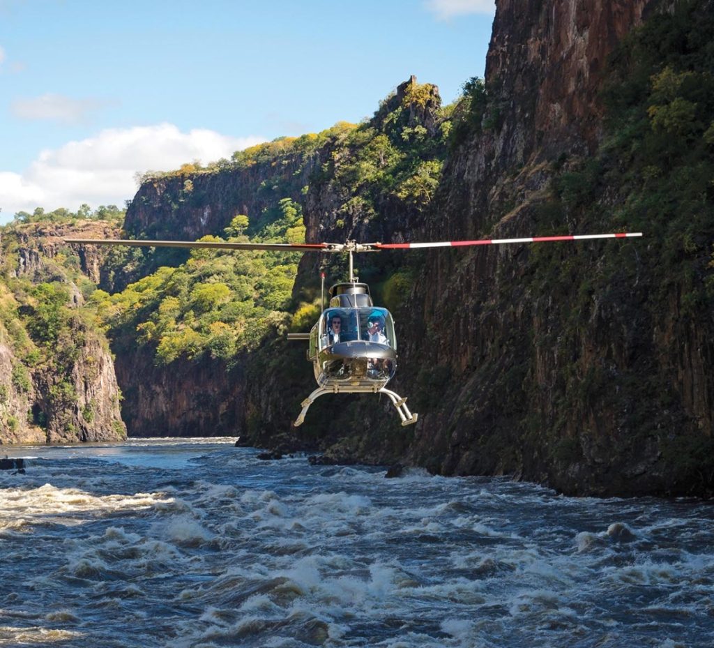 A helicopter flying over river Zambezi through the gorge between Zimbabwe and Botswana.