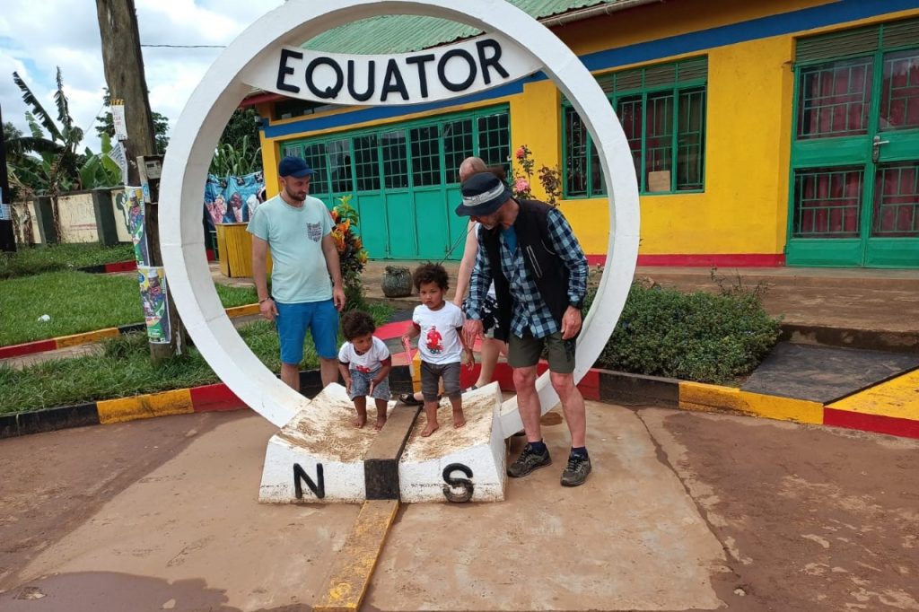 A family taking photos at the equator monument during their safari in Uganda.
