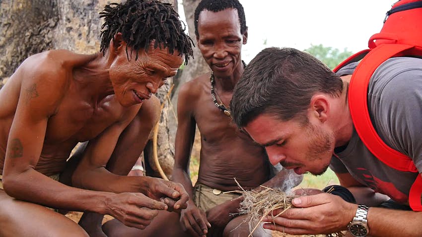 The San bushmen teaching a tourist how to make fire in Namibia